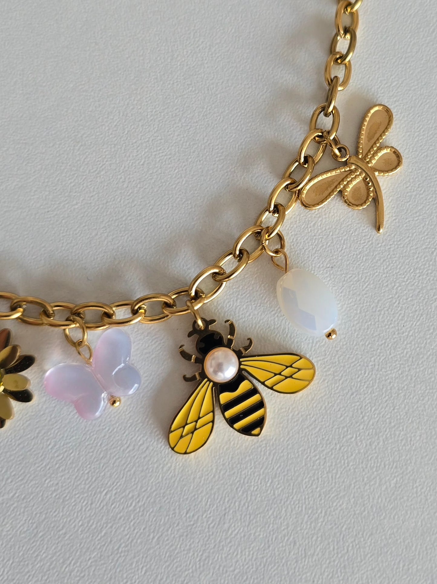 Bracelet fantaisie chic en acier inoxydable doré avec pendentifs colorés et détails raffinés.