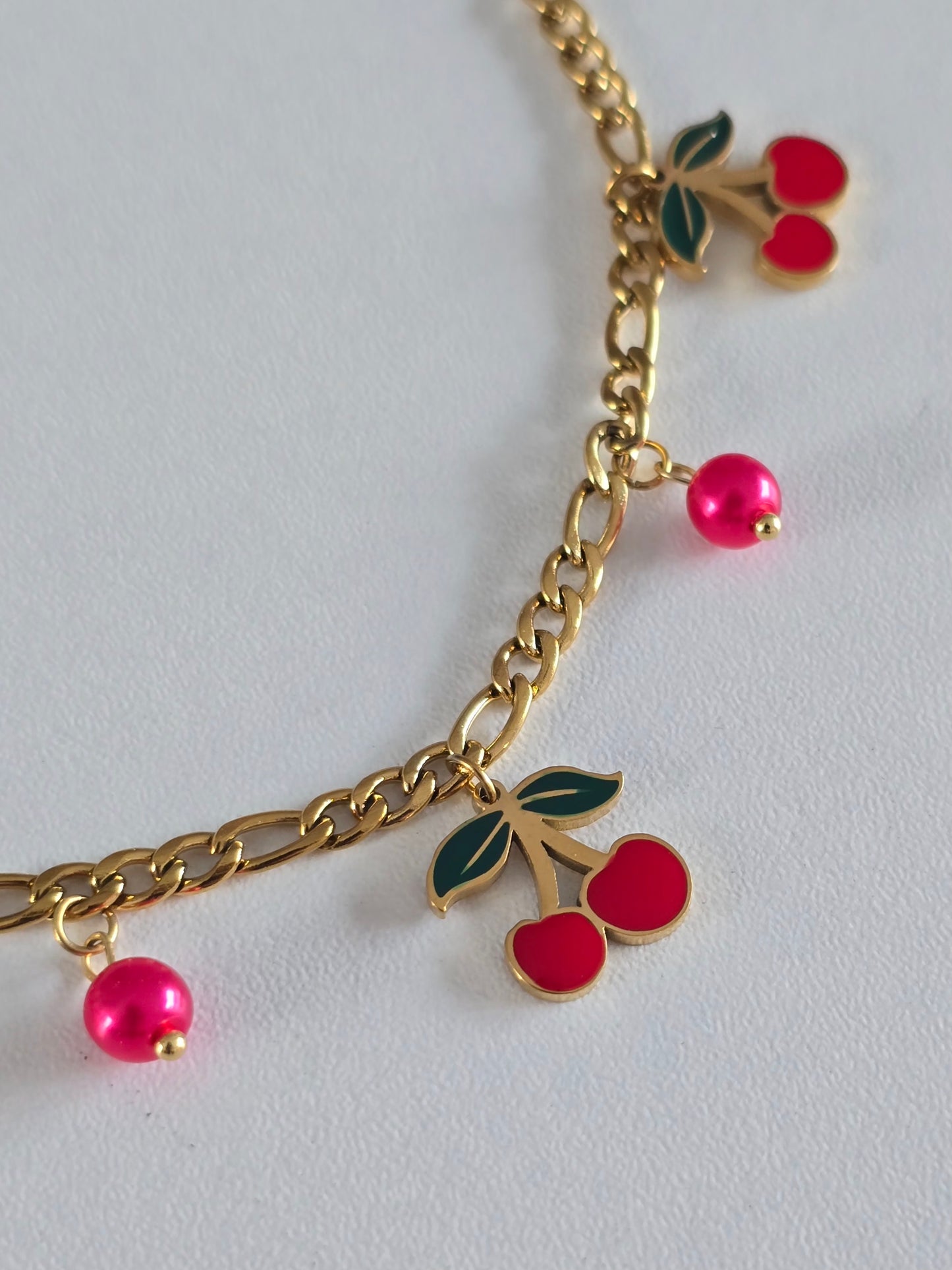 Bracelet en acier inoxydable orné de pendentifs cerises rouges et maillons dorés