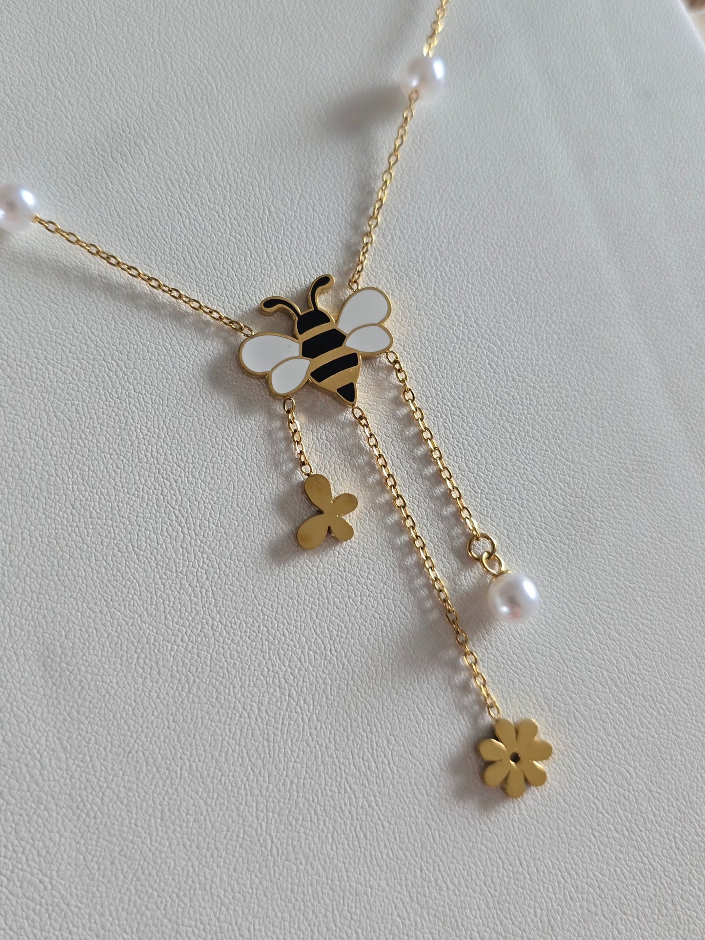 bijou doré raffiné pour femme avec symboles nature : abeille, fleur, papillon et perle