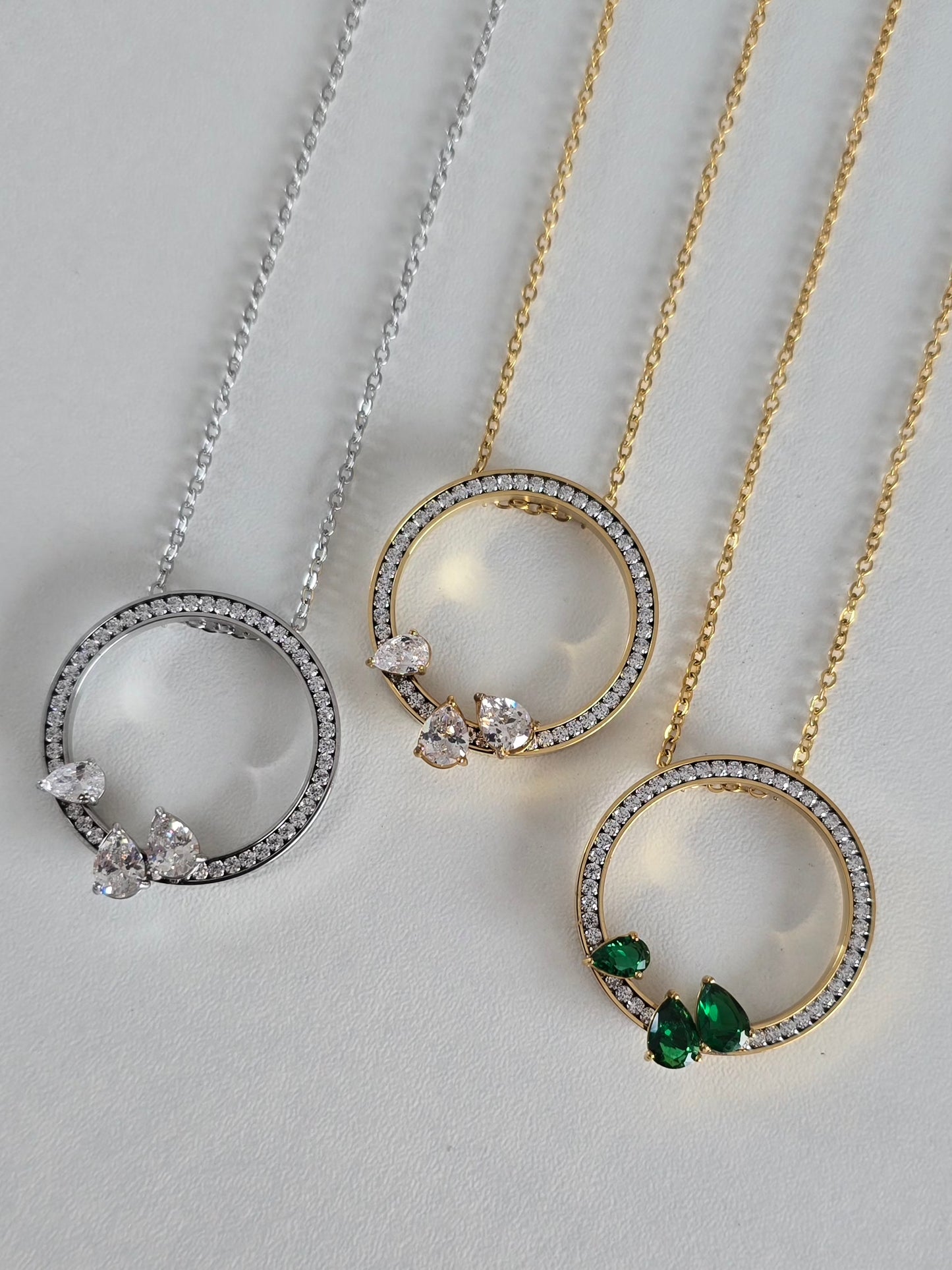 Collier Oriana en acier inoxydable : cercle pavé de strass, décliné en argenté, doré et doré/vert. Élégant, durable et intemporel.