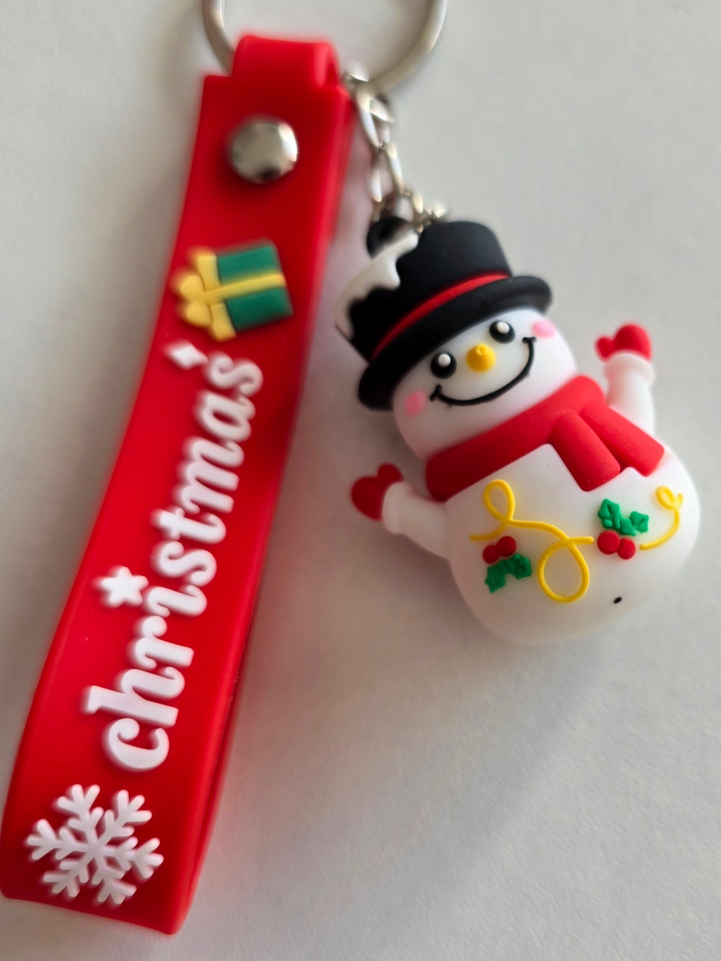 détail du porte-clés Snowy avec sourire, houx et écharpe rouge