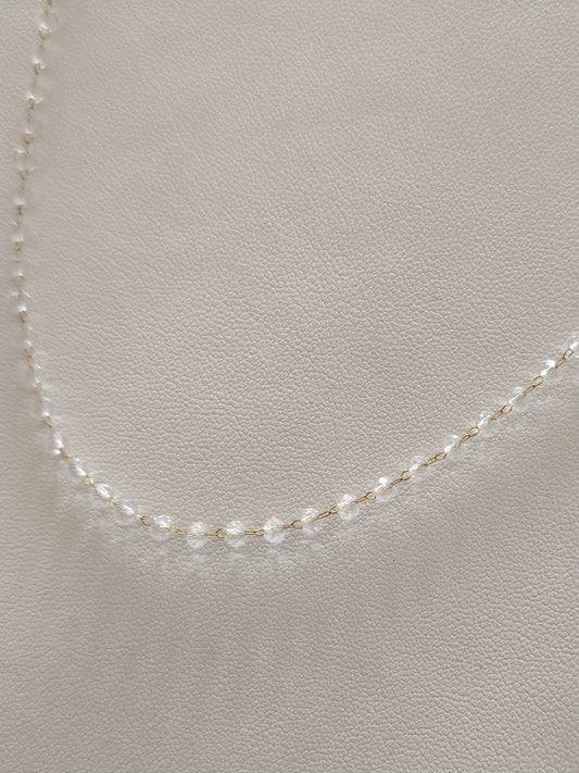 Détail du collier Clarity avec chaîne dorée et perles transparentes
