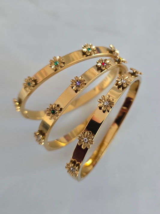 Vue rapprochée des bracelets Margarita dorés avec fleurs 3D décoratives aux détails raffinés.