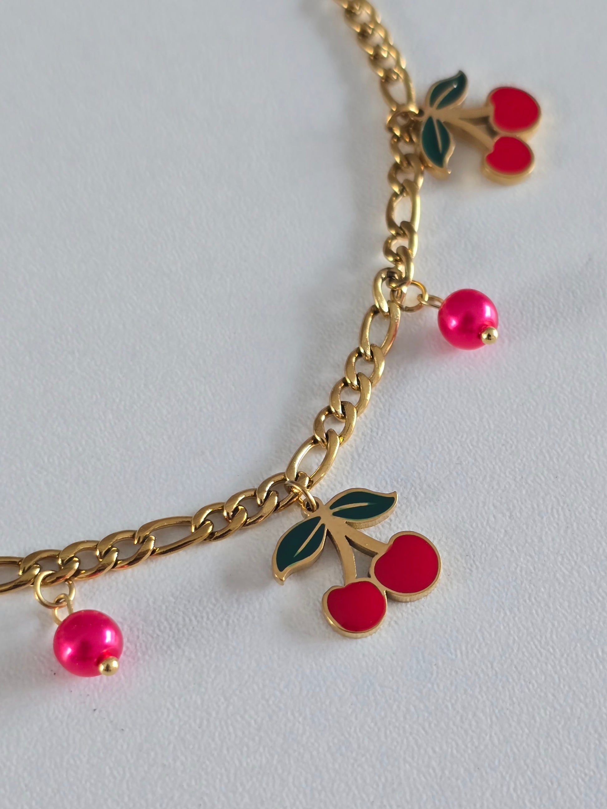 Bracelet en acier inoxydable orné de pendentifs cerises rouges et maillons dorés 