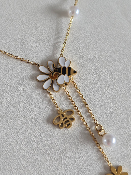 gros plan sur le pendentif abeille noire et dorée posée sur une fleur blanche 