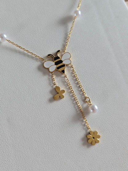 bijou doré raffiné pour femme avec symboles nature : abeille, fleur, papillon et perle