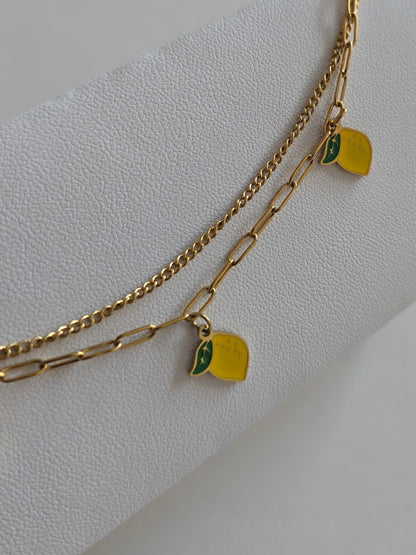 gros plan sur un bracelet de cheville doré double chaîne avec citrons 