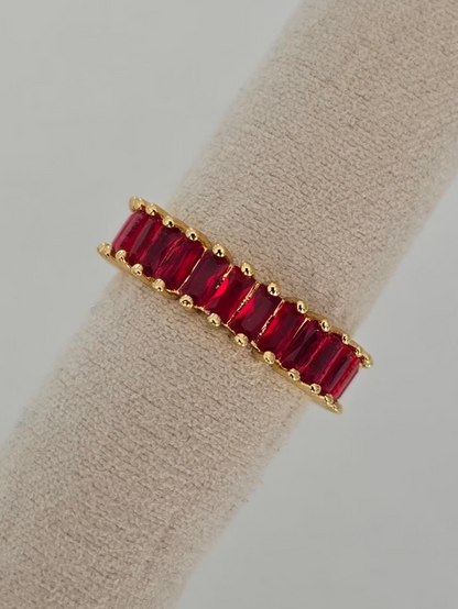 bague dorée Lumired avec pierres rouges rectangulaire présentée sur un coussin d'exposition