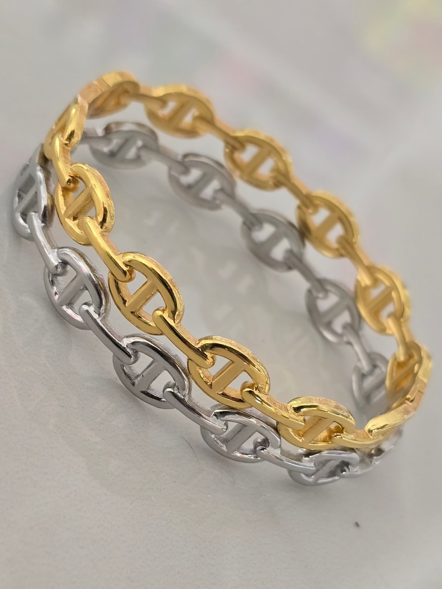 Bracelet rigide Livia en acier inoxydable, disponible en finition dorée ou argentée, design à. maillons élégants.