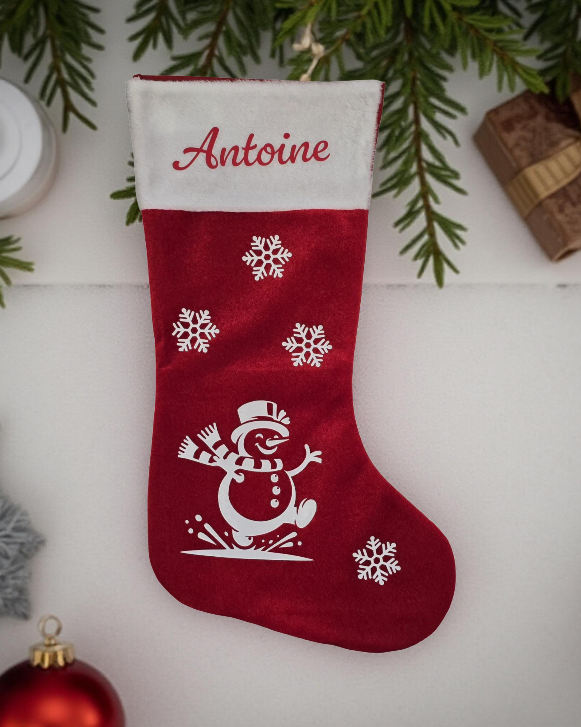 Chaussette de Noël personnalisées pour Antoine, avec flocons et bonhomme de neige qui court.
