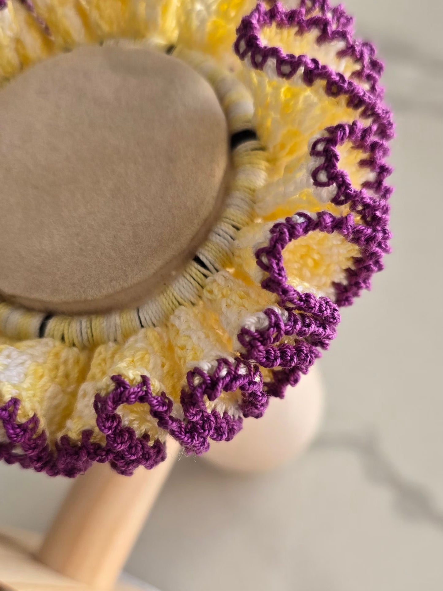 Chouchou en crochet jaune et violet présenté sur support 