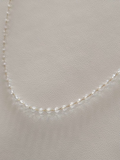 Détail du collier Clarity avec chaîne dorée et perles transparentes 