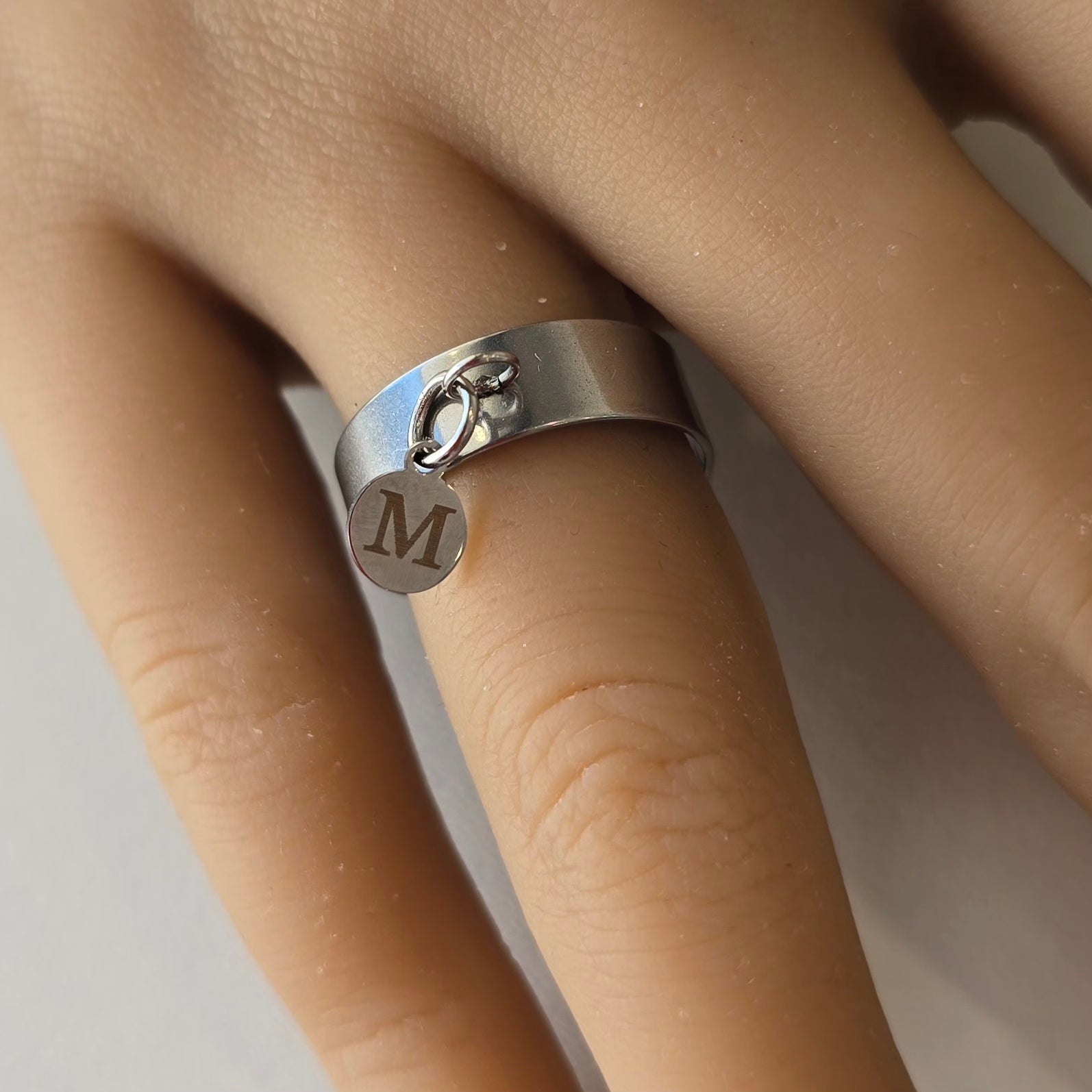 Bague porté en acier inoxydable, avec breloque personnalisée, ici la lettre M