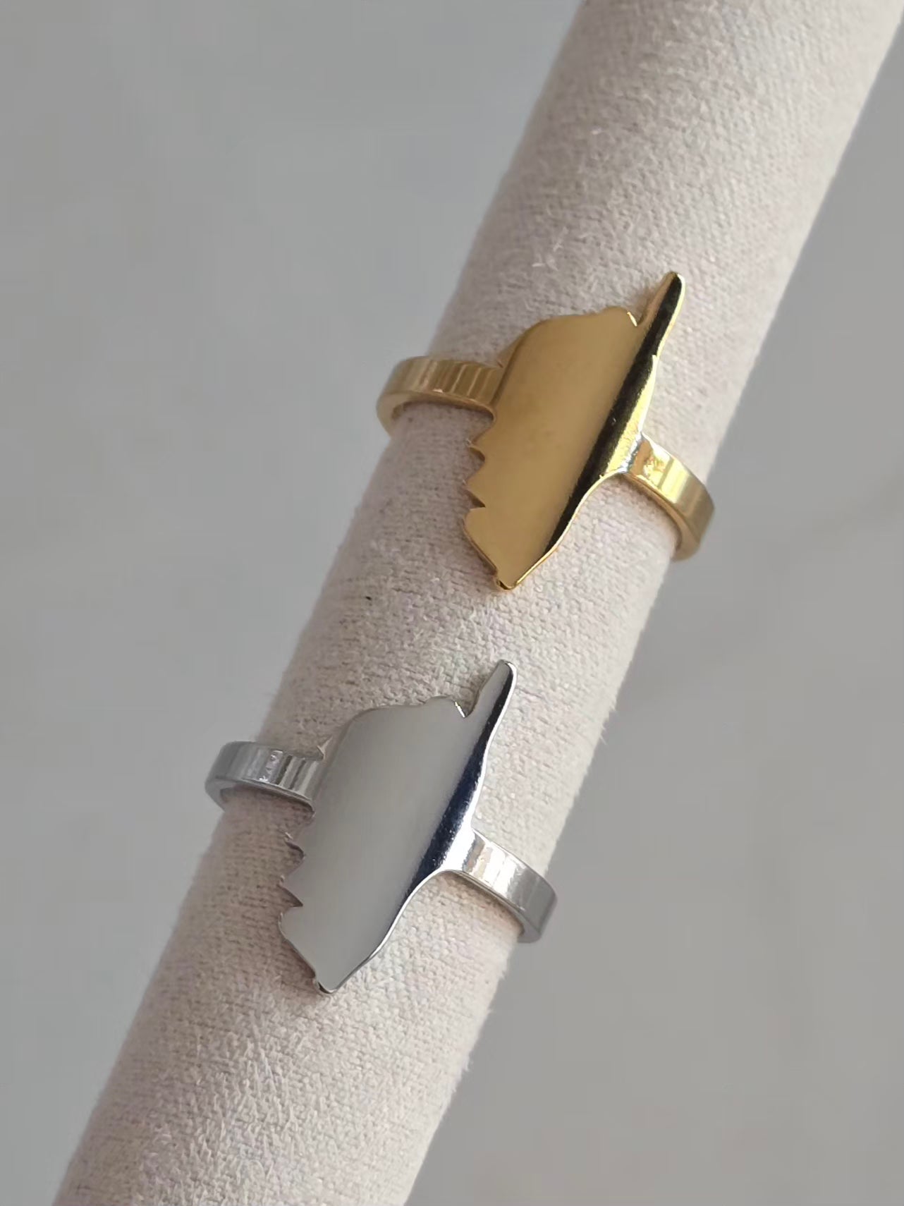 Bague Isula en acier inoxydable ajustable avec motif Corse, présentée en version dorée et argentée sur présentoir.