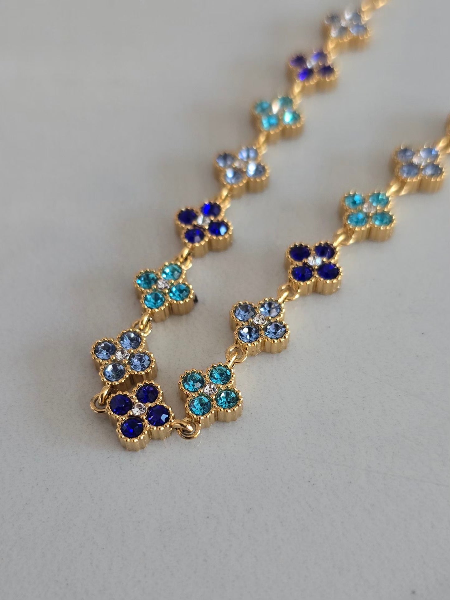 Bracelet Princesa bleu avec motifs fleurs à quatre pétales sertis de strass scintillants.