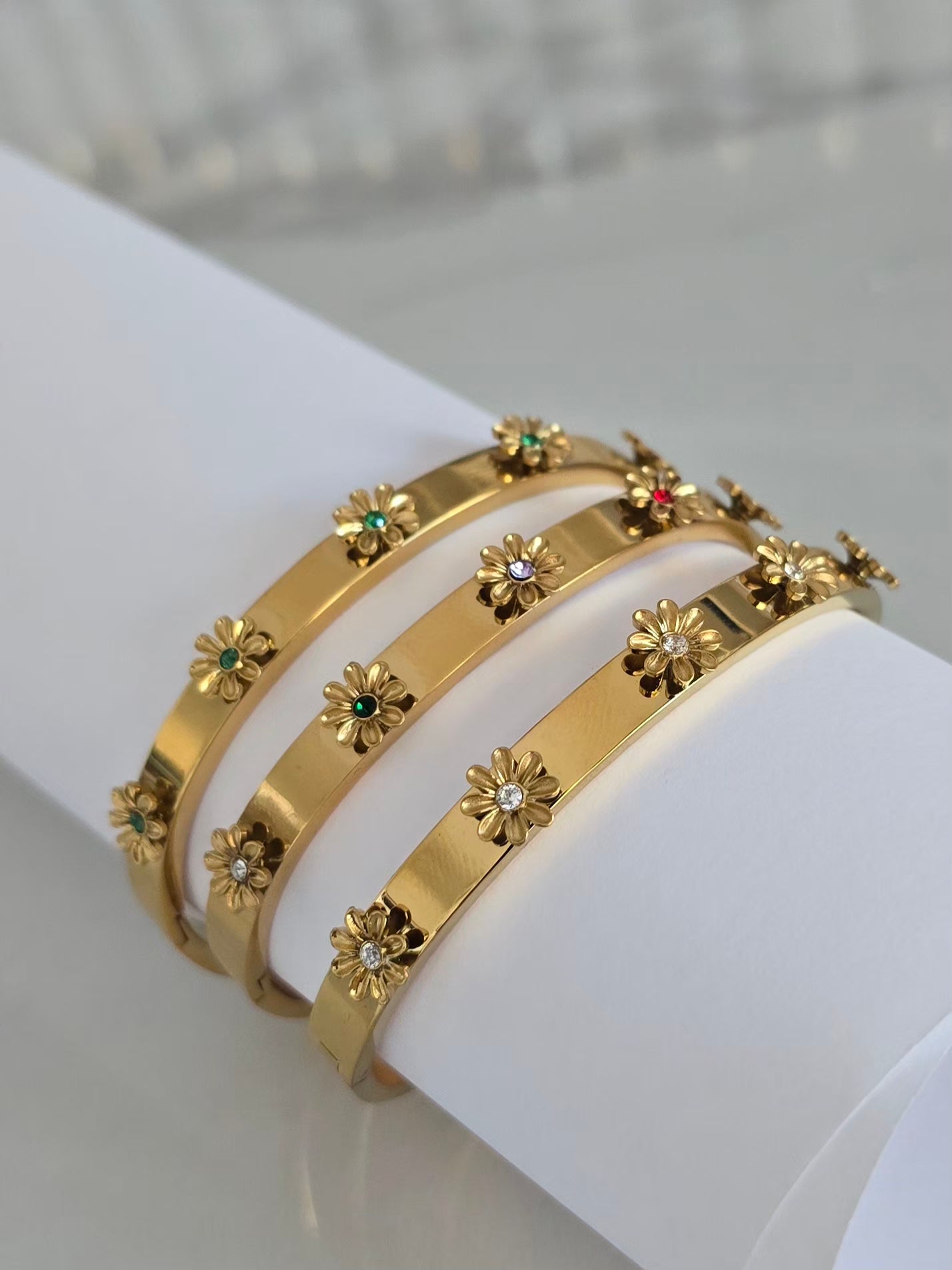 Bracelets joncs Margarita dorés présentés ssur un support blanc mettant en valeur leurs fleurs 3D