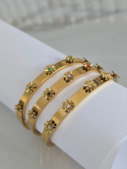 Bracelets joncs Margarita dorés présentés ssur un support blanc mettant en valeur leurs fleurs 3D
