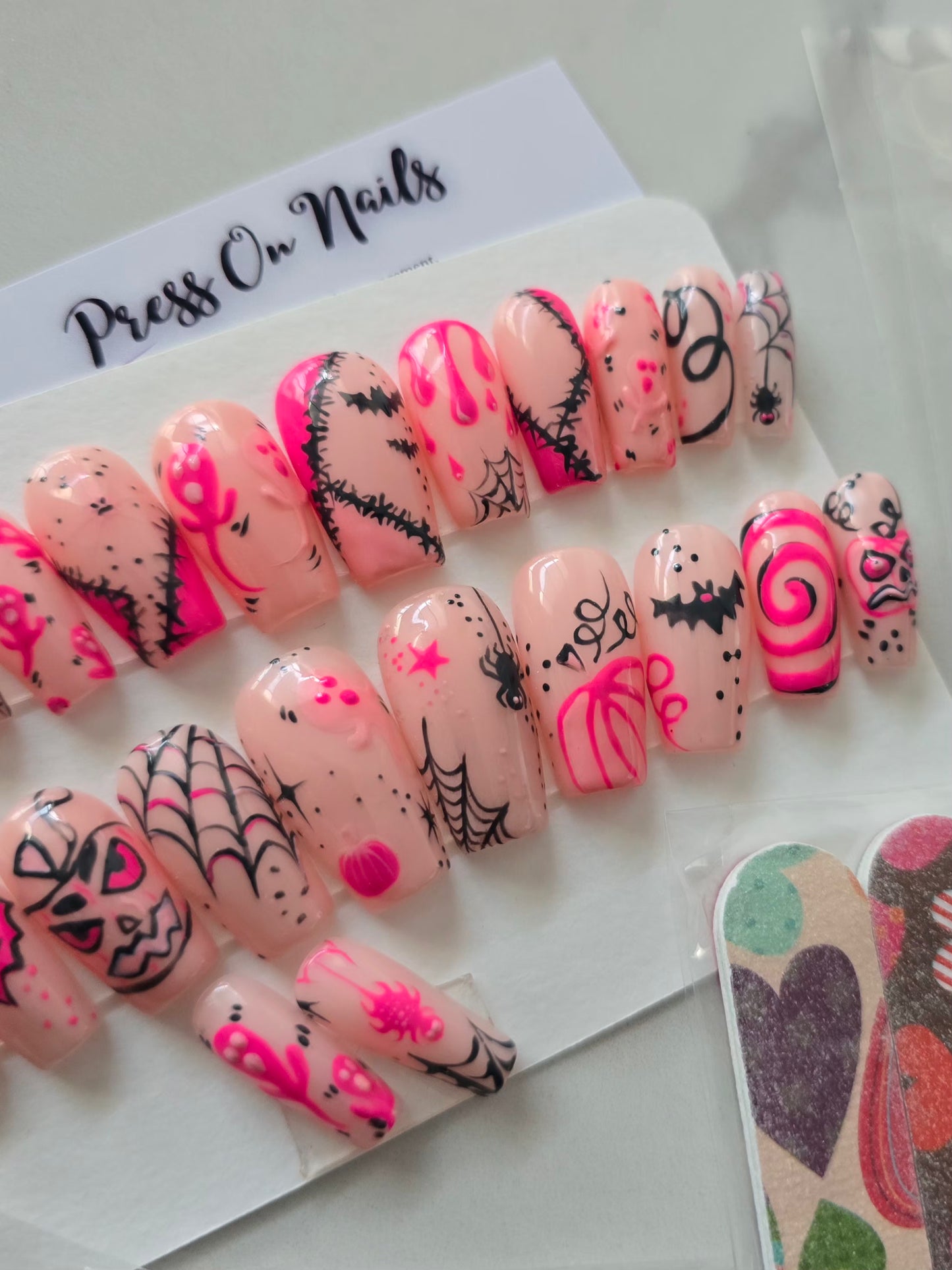 Capsules d'ongles roses décorées à la main avec motifs Halloween noirs et roses - Press On Nails réutilisables.