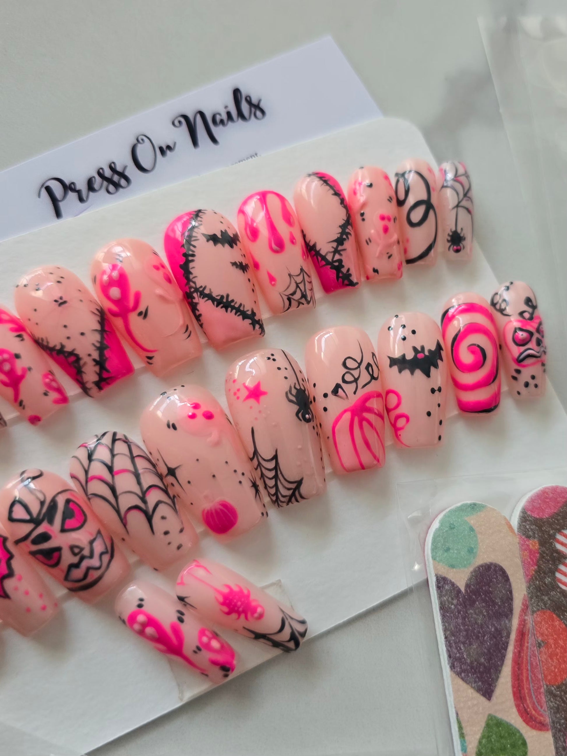 Capsules d'ongles roses décorées à la main avec motifs Halloween noirs et roses - Press On Nails réutilisables.