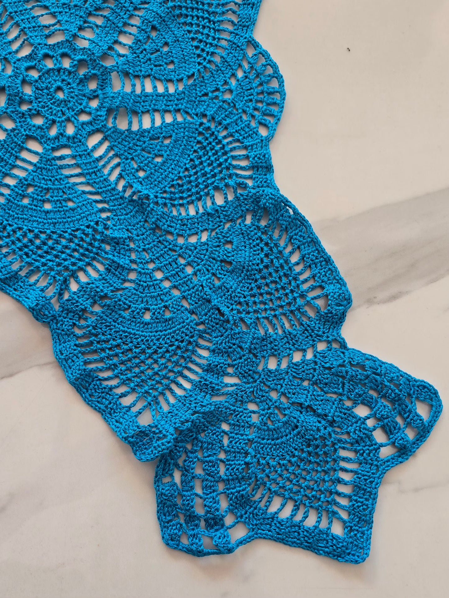 gros plan sur les détails ajourés du chemin de table bleu en crochet