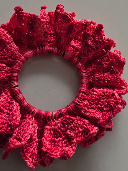 Chouchou volumineux en coton rose crocheté.