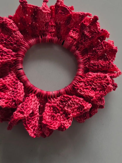 Chouchou rose en crochet fait main avec détail artisanal et volants.