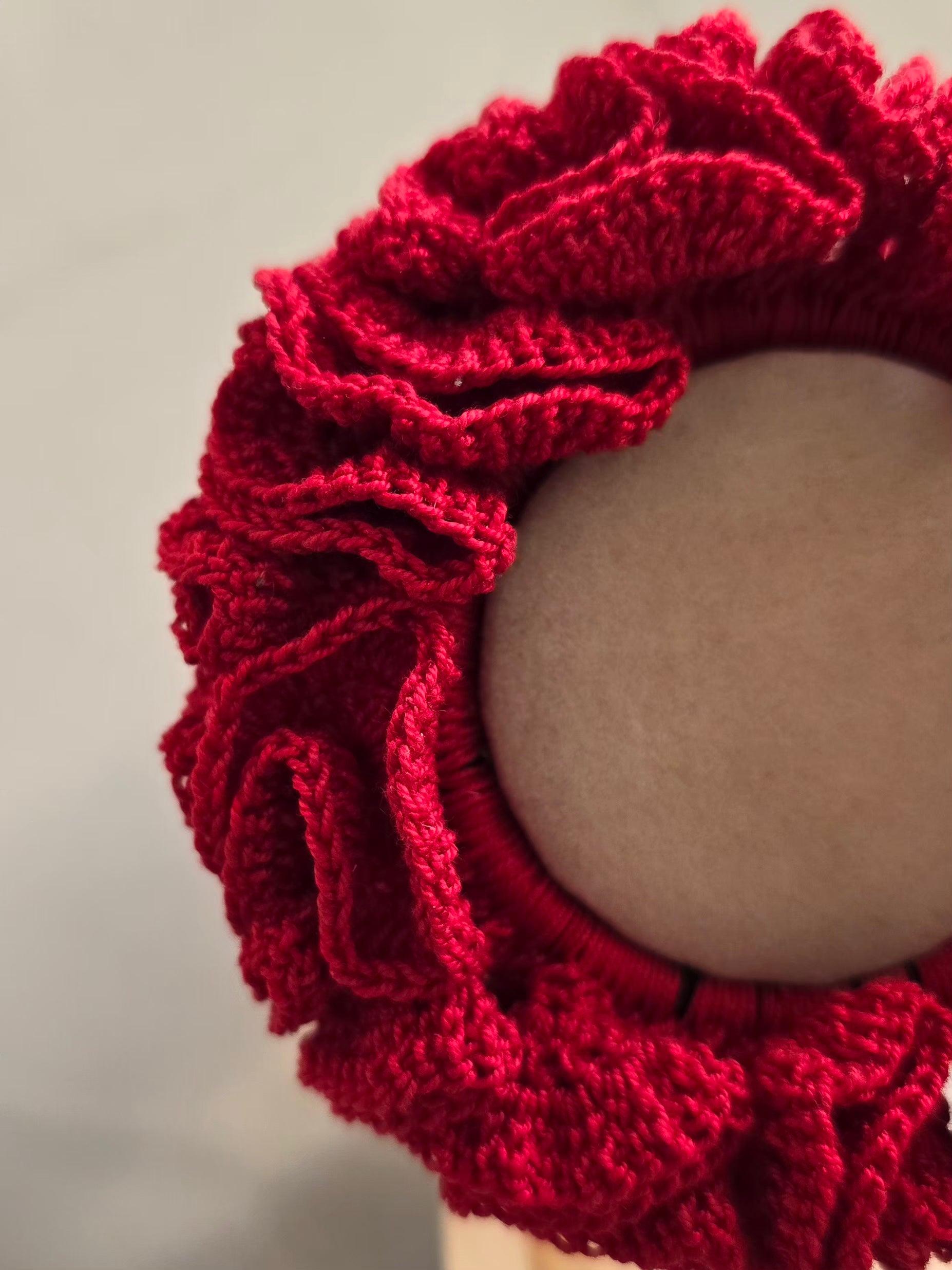 Chouchou rouge en crochet présenté sur support 