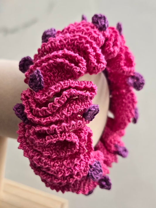 Chouchou volumineux rose artisanal avec détails violets au crochet.