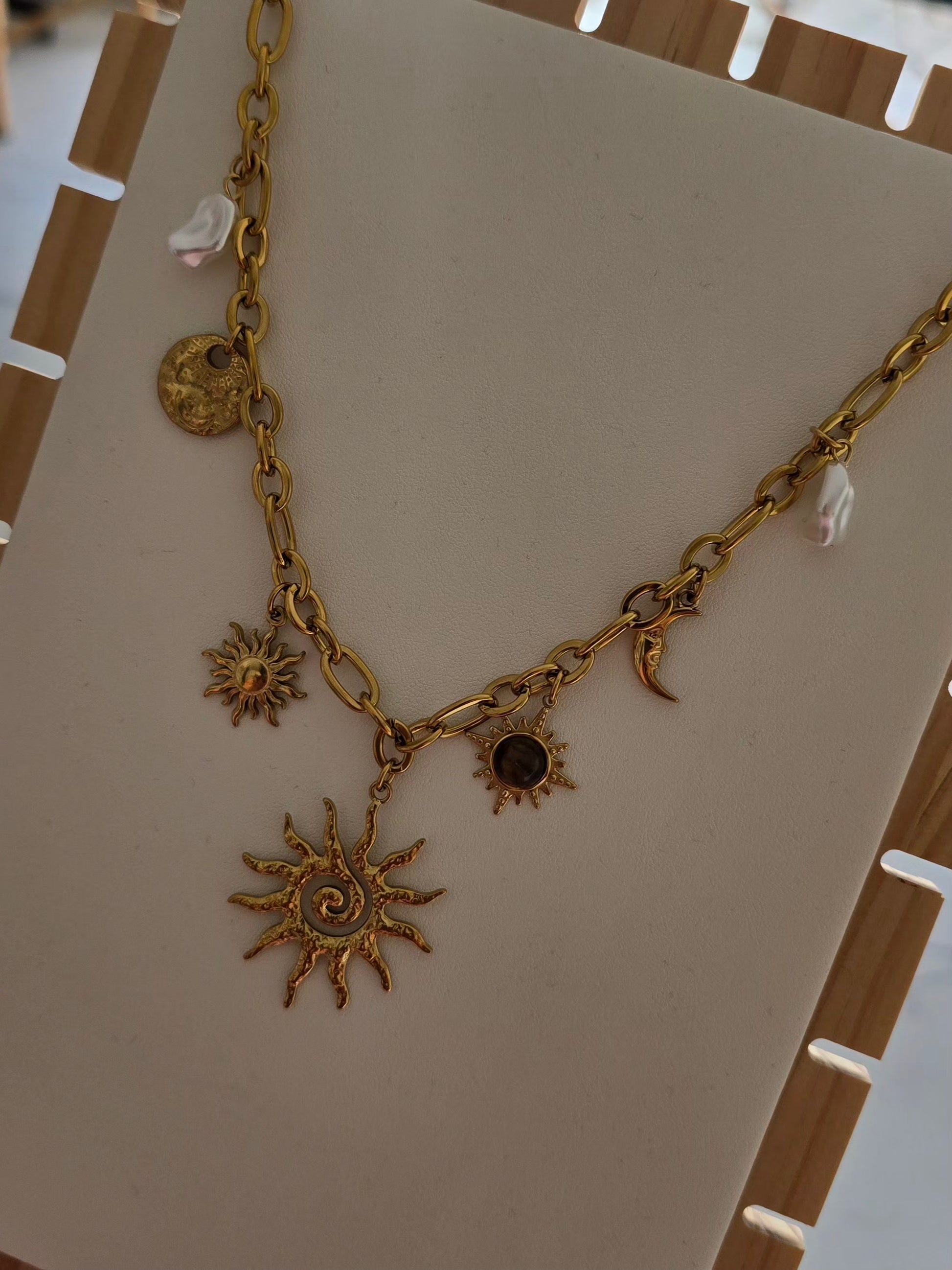 Détail des charms soleil, lune et perles du collier Soléa en acier inoxydable.