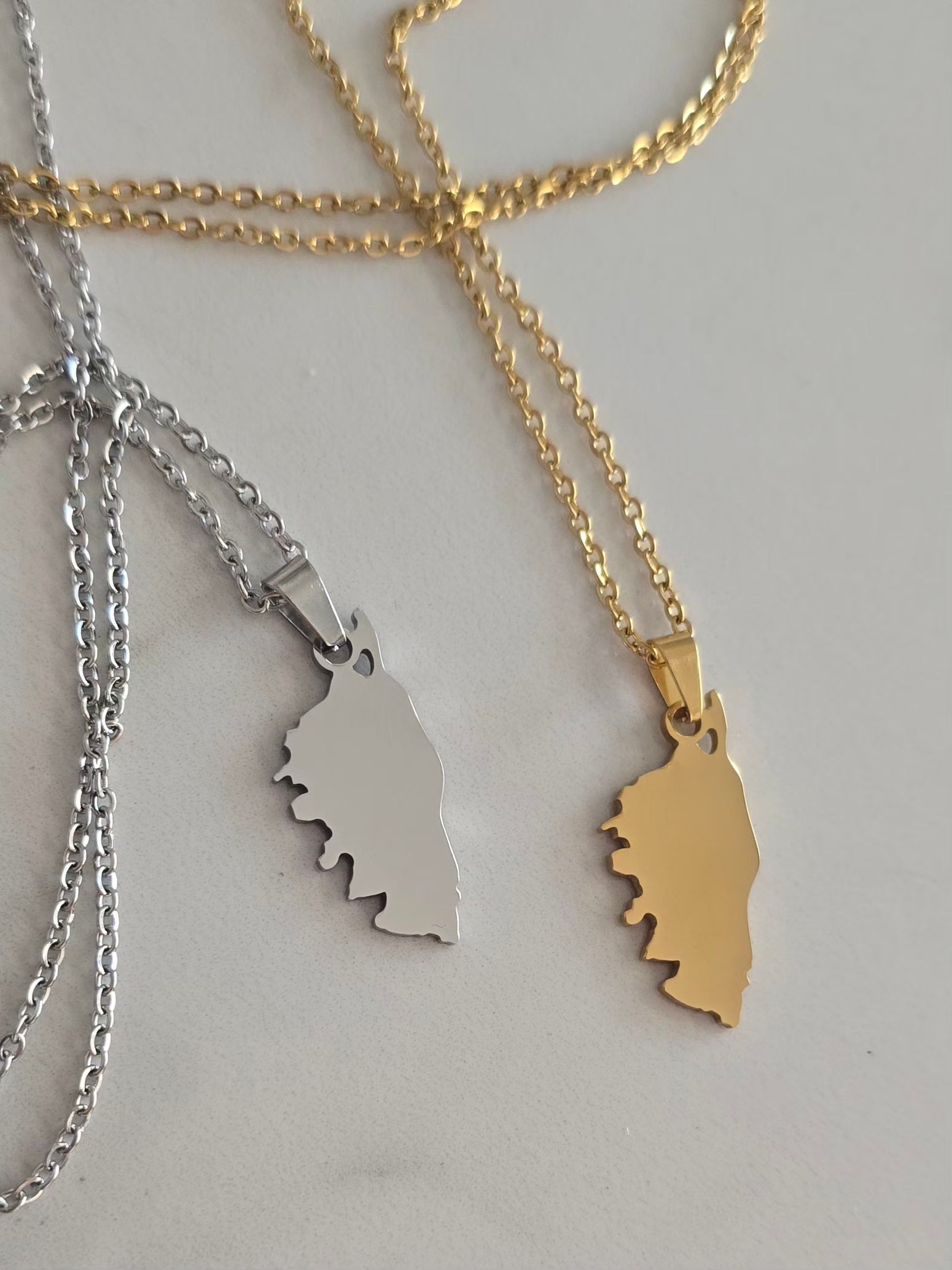 Comparatif des colliers Isula doré et argenté en acier inoxydable représentant la Corse.