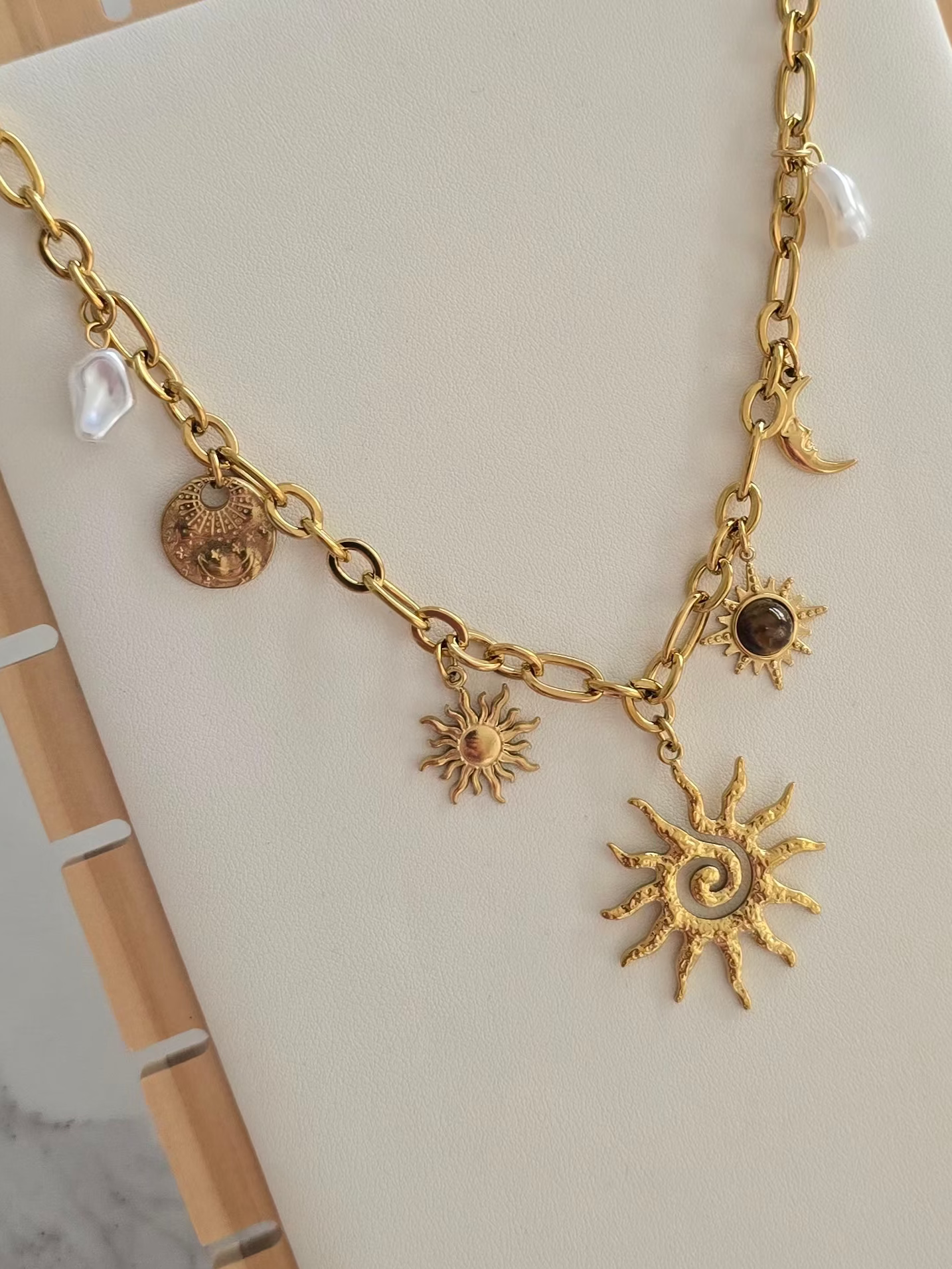 Collier bohème Soléa doré avec grand pendentif soleil et breloques célestes.