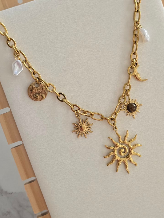 Collier bohème Soléa doré avec grand pendentif soleil et breloques célestes.