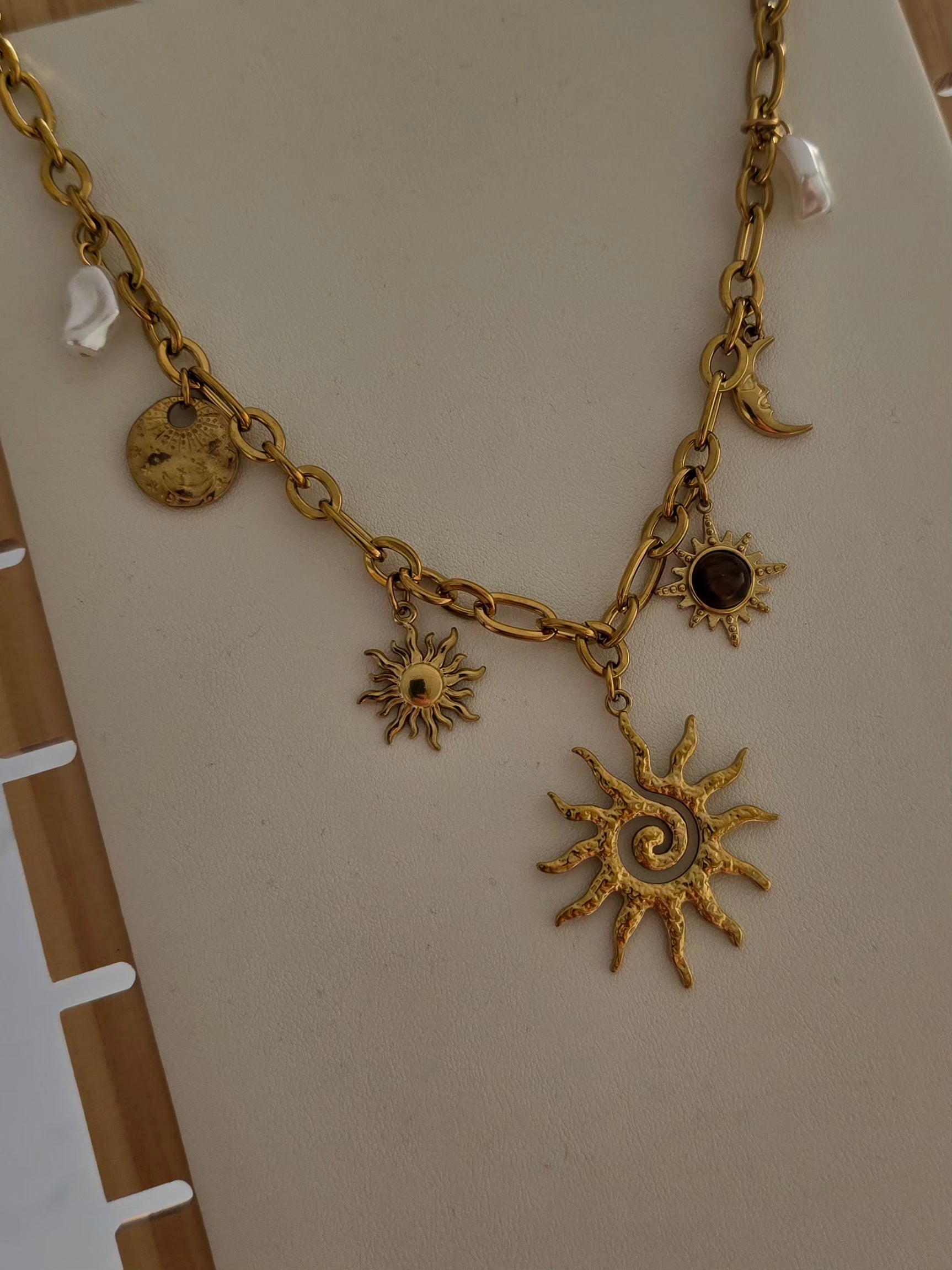 Grand pendentif soleil du collier Soléa avec chaîne dorée et charms.