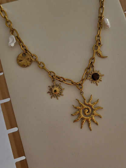Grand pendentif soleil du collier Soléa avec chaîne dorée et charms.