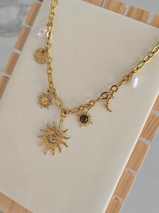Collier Soléa en acier inoxydable doré avec charms soleil, lune et perles blanches.