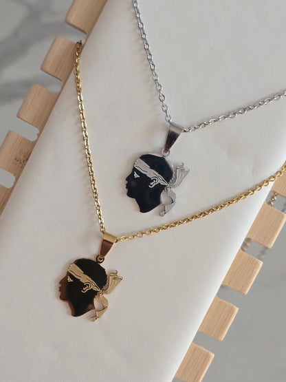 Colliers Tête de Maure doré et argenté présentés sur un support à bijoux.