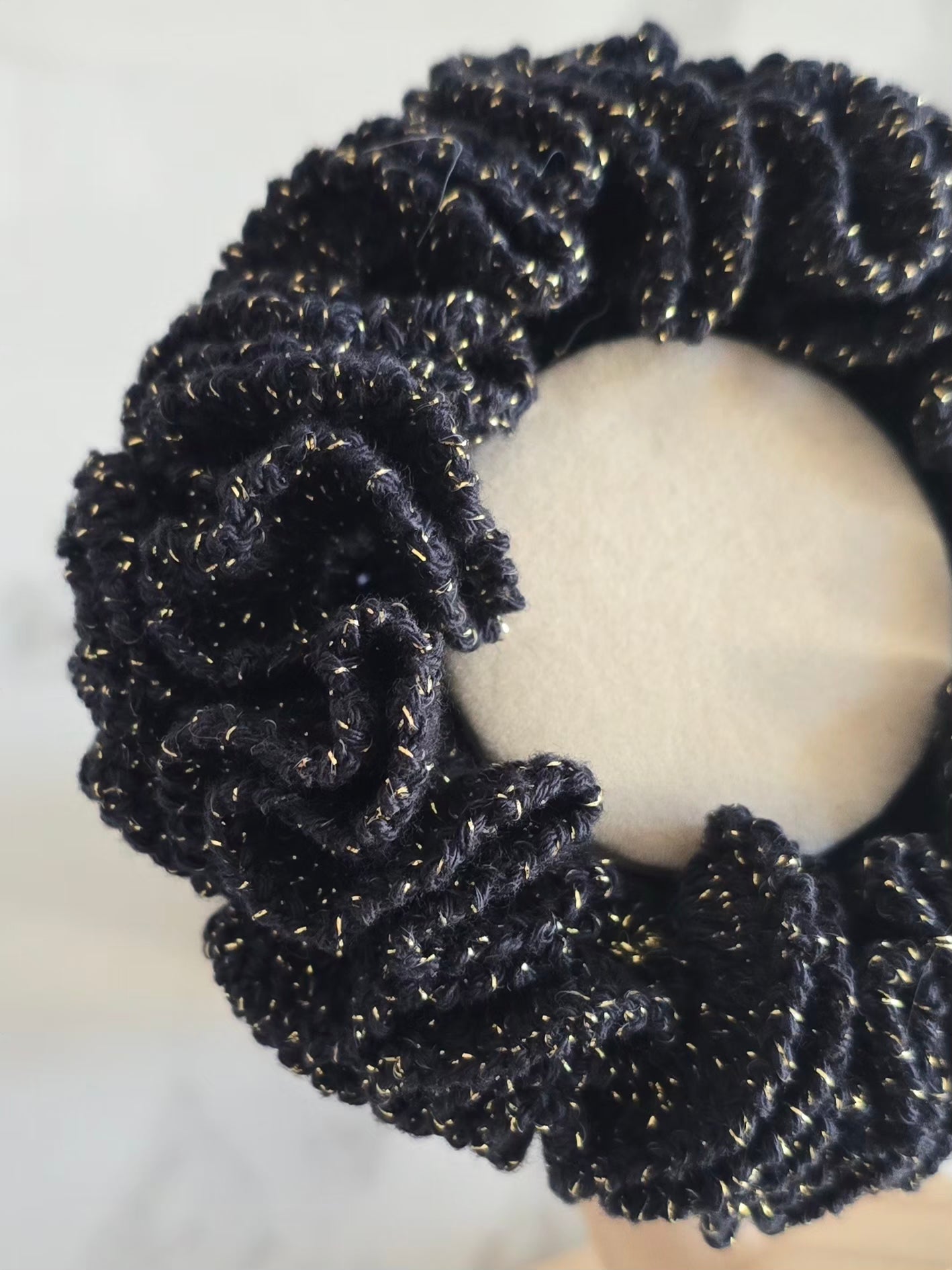 Détail des fils dorés scintillants sur un chouchou noir au crochet