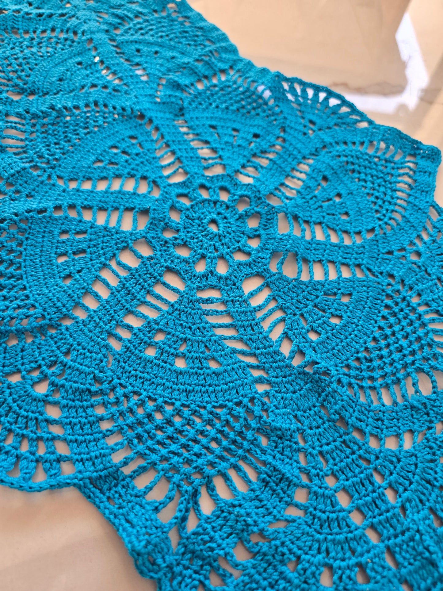 Détail du motif rond central du chemin de table en crochet bleu