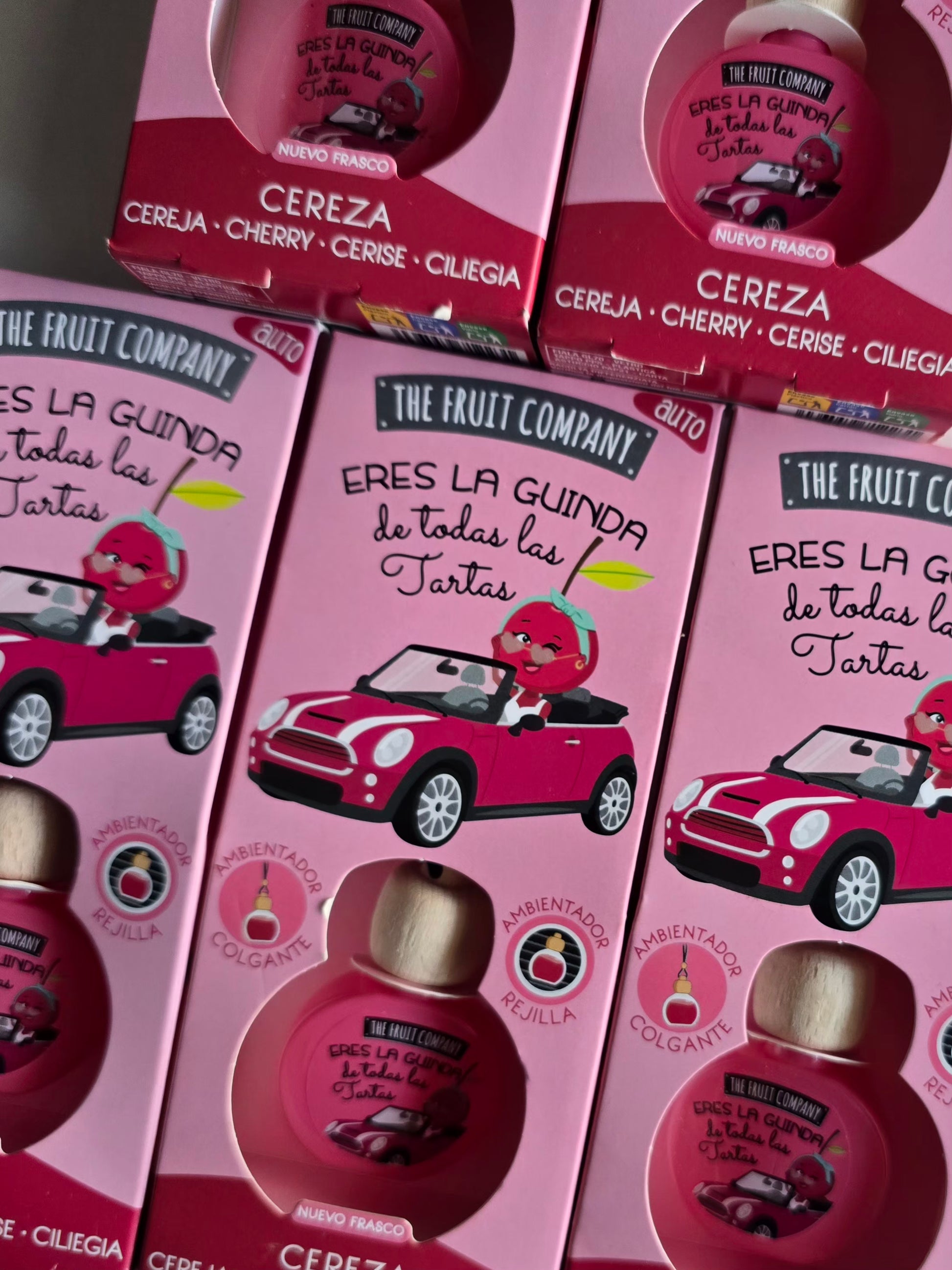 Parfum d'ambiance pour voiture senteur cerise présenté dans son coffret rose The Fruit Company, idéal pour une voiture fraîche et parfumée.