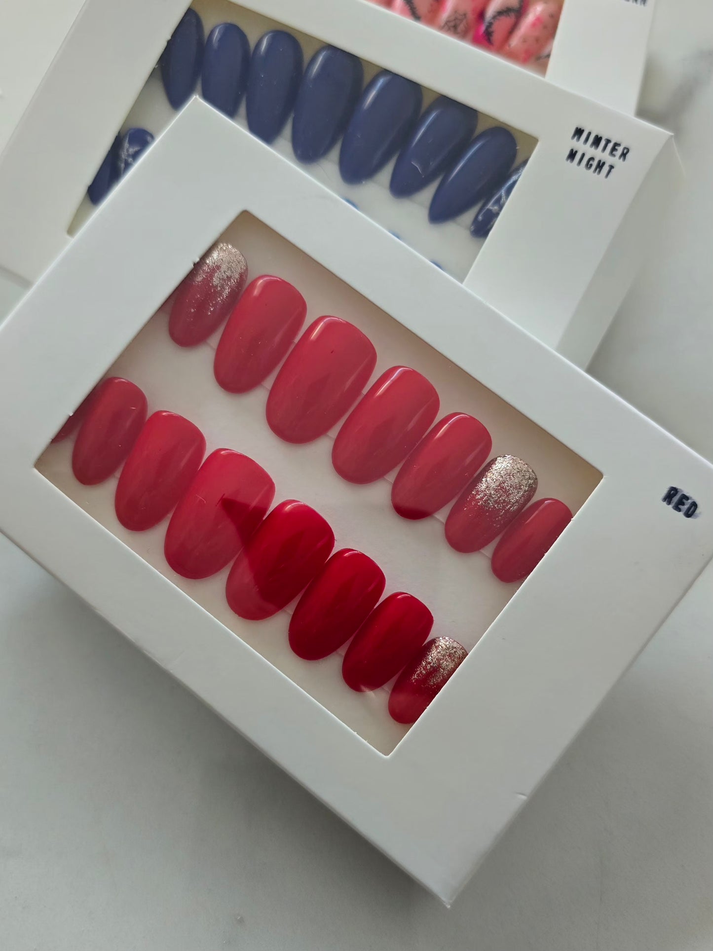 Boîte blanche contenant les Press On Nails Red - ongles rouges élégants et faciles à poser.